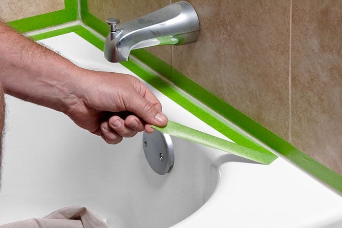 how to caulk a bathtub — cracked and peeling bathtub caulk line before removal and replacement