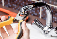 how to fix a leaky faucet — close up of dripping kitchen faucet wasting water before repair