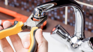 how to fix a leaky faucet — close up of dripping kitchen faucet wasting water before repair