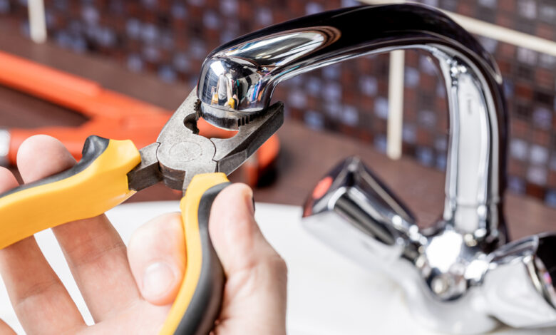 how to fix a leaky faucet — close up of dripping kitchen faucet wasting water before repair