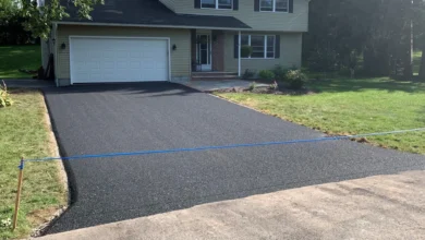 asphalt driveway installation process with paving machine and workers leveling hot asphalt