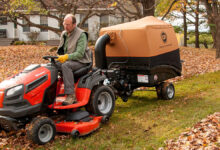Person using a leaf vacuum to clean up fallen autumn leaves in a backyard